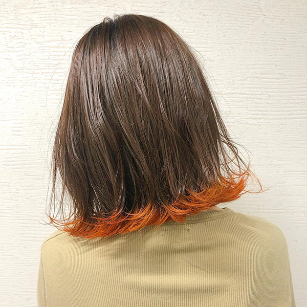 オレンジの裾カラーを施した女性のヘアスタイル