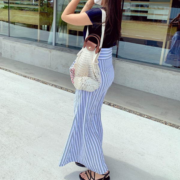 LONGCHAMPで展開されている、ル プリアージュ フィレ トップハンドルバッグのベージュを持ったきれいめカジュアルコーデの女性