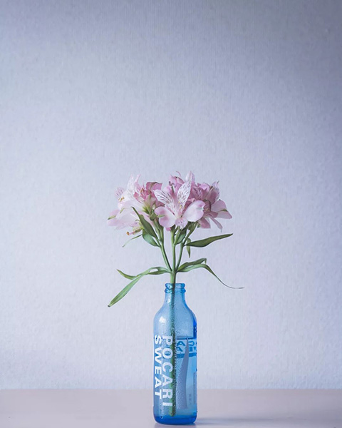 循環型プラットフォーム「Loop」より登場した「ポカリスエット リターナブル瓶 250ml」の空き瓶に花を生けた様子