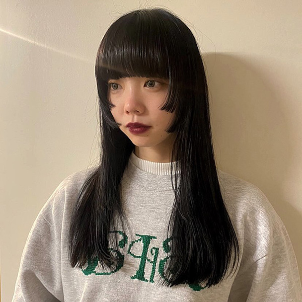 黒髪ロングのレイヤーヘアにワイドバングの女性