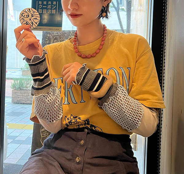 古着屋発のリメイクブランド「Chinatsu Aoyama」のトップスを着て、ショップカードを持つ女性