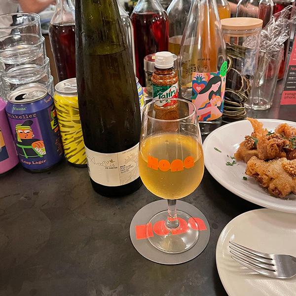 渋谷・神泉にある立ち飲みバー「Hone Stand」の、ロゴ入りグラスに入ったワインと唐揚げ