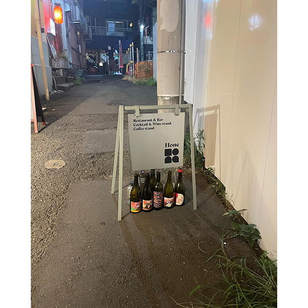 渋谷・神泉にある立ち飲みバー「Hone Stand」の、ワインボトルと一緒に置かれた路地看板