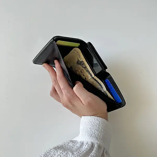 『otona MUSE 2023年12月号』の表紙と付録の「Deuxieme Classe シンプル&ハイクオリティ 究極のミニ財布」のフラップ部分にお札とカードを入れ、上から撮影している画像