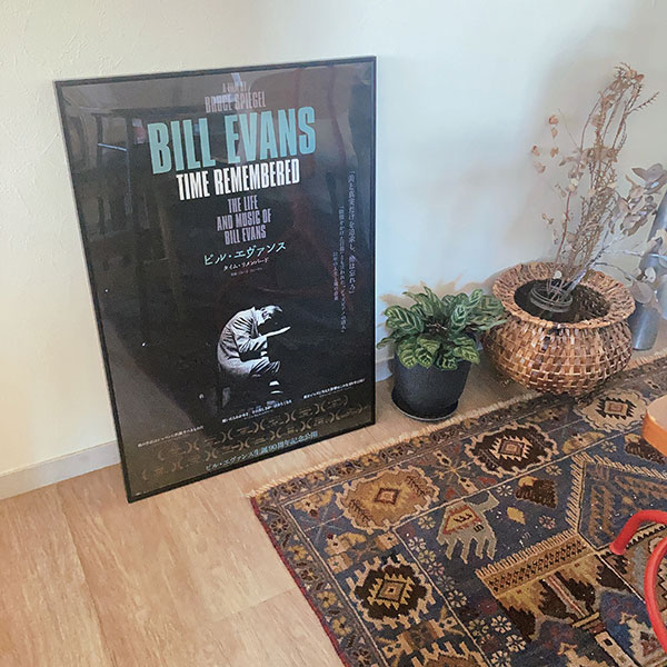 エスニックな柄のラグと、額縁に入れた状態で床に置かれた、ビル・エヴァンスの映画ポスター