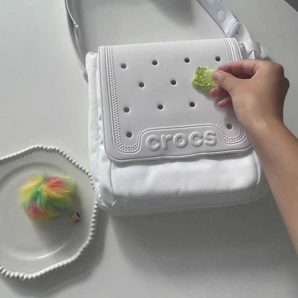 「crocs（クロックス）」の「クロックス クラシック クロスボディ」（カラー：『ホワイト』）にジビッツチャームをのせている様子