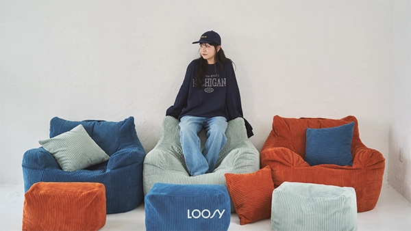 ソファブランド「LOOSY」の「HUGME 1人掛けビーズソファ」に座る女性