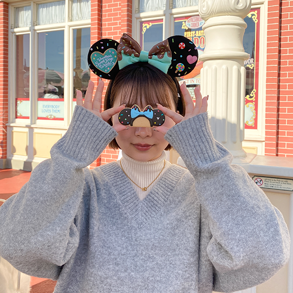 東京ディズニーランドの「ミニーマウスのカチューシャクッキー」を使って写真を撮る女性